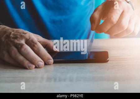 Man applying protective screen protector on his smartphone touchscreen Stock Photo
