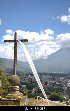 Distant view of the Volcano El Fuego o Acatenango with cross in the foreground in Antigua, Guatemala Stock Photo