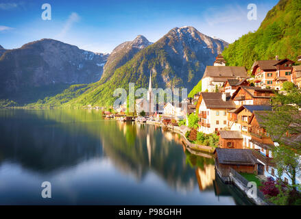 Classic postcard view of famous Hallstatt lakeside town reflecting in Hallstattersee lake in the Austrian Alps in scenic morning light on a beautiful  Stock Photo