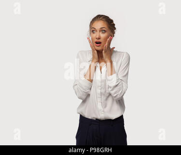 A very surprised business lady dressed in classic office clothes brought her hands to her face. Surprise from sales. Stock Photo