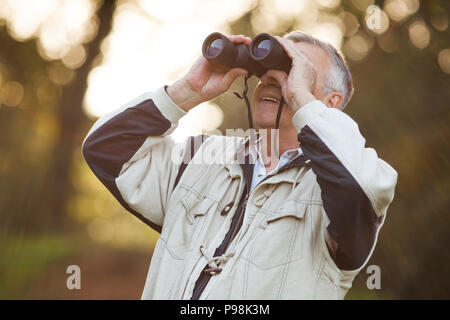 Senior man looking through binoculars in park Stock Photo