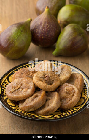 Dish with dried figs and ripe fresh ones on the background Stock Photo
