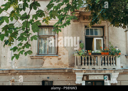 Shapnel marks from the Siege of Sarajevo still visible on the exterior of a building next to a balcony and window of a house in 2018 Stock Photo
