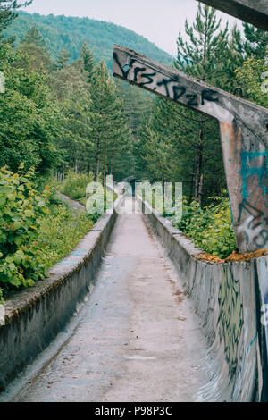 the now-disused concrete of the 1984 Sarajevo Olympic Bobsleigh and Luge Track curves through the forest, covered in graffiti Stock Photo