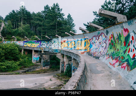 the now-disused concrete of the 1984 Sarajevo Olympic Bobsleigh and Luge Track curves through the forest, covered in graffiti Stock Photo