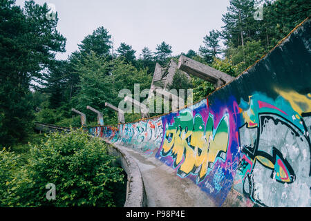 the now-disused concrete of the 1984 Sarajevo Olympic Bobsleigh and Luge Track curves through the forest, covered in graffiti Stock Photo