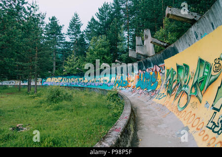 the now-disused concrete of the 1984 Sarajevo Olympic Bobsleigh and Luge Track curves through the forest, covered in graffiti Stock Photo