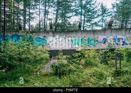 the now-disused concrete of the 1984 Sarajevo Olympic Bobsleigh and Luge Track curves through the forest, covered in graffiti Stock Photo