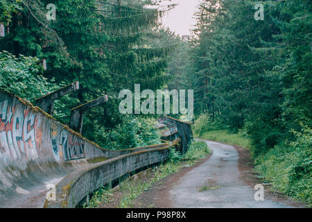 the now-disused concrete of the 1984 Sarajevo Olympic Bobsleigh and Luge Track curves through the forest, covered in graffiti Stock Photo