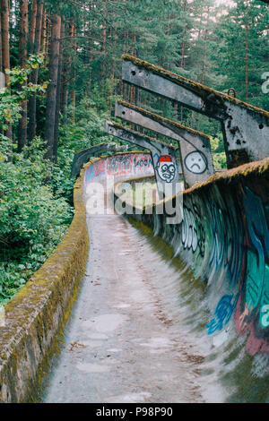 the now-disused concrete of the 1984 Sarajevo Olympic Bobsleigh and Luge Track curves through the forest, covered in graffiti Stock Photo