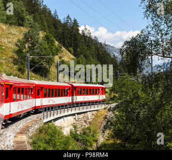 Red and white Matterhorn Gotthard Bahn train and carriages on the narrow guage railway line in the Mattertal en route from Zermatt to Visp Stock Photo