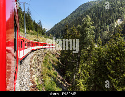 Red and white Matterhorn Gotthard Bahn train and carriages on the narrow guage railway line in the Mattertal en route from Zermatt to Visp Stock Photo