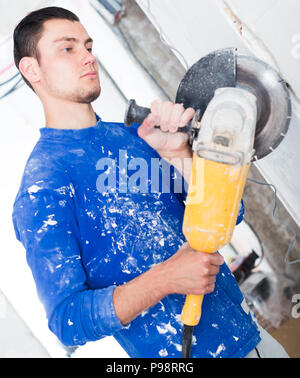 Construction worker cutting concrete wall by using handheld circular saw Stock Photo