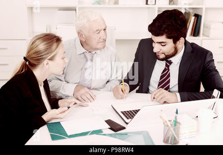 Managers are writing financial reports and discussing with mature boss in the office. Stock Photo