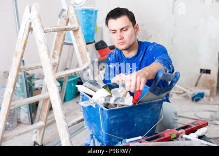 Young handyman searching in his toolbox for necessary tools Stock Photo