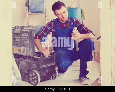 attentive builder handyman choosing necessary tool in toolbox Stock Photo