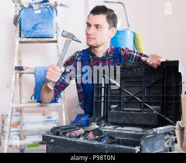 Worker repairing room and looking for necessary tool in toolbox Stock Photo