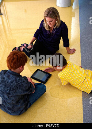 Fifth graders use internet and mobile device like an Apple iPad to research a topic for class. The research then is used for writing a paper on the computer, or making a Powerpoint presentation. Al to get a good grade in school Stock Photo