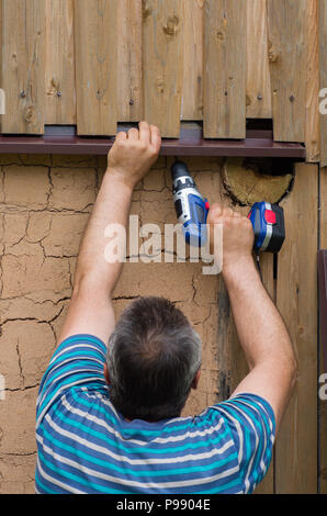 The person is engaged in construction with the help of an electric screwdriver - works on the spot with the help of a hand tool. Construction works. Stock Photo