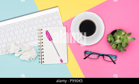 Creative flat lay photo of workspace desk. Top view office desk with notepad, wireless keyboard, succulent plant, coffee cup and glasses on pastel col Stock Photo