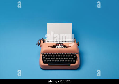 Old typewriter with a paper sheet on the blue background in the studio. Horizontal. Stock Photo