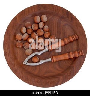 Nutcrackers and hazelnuts on beautiful wooden plate, isolated on white. Typical Christmas, seasonal treat. Stock Photo