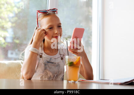 Blonde-haired girl feeling happy while having video chat Stock Photo