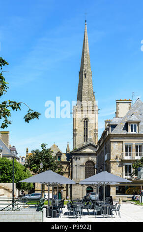 Place des Freres Lamennais with a terrace with parasols in the foreground and the steeple of Saint-Vincent of Saragossa cathedral in the background. Stock Photo