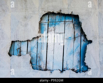 Photo of concrete wall with hole and blue fence Stock Photo