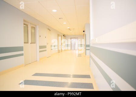 The corridor of the hospital is lit by bright natural light and decorated with modern materials, shot on a wide-angle lens. Stock Photo