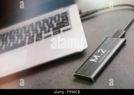 Enclosure Case for M.2 SSD is connected to modern aluminium laptop Stock Photo