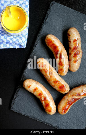Hot Grilled German Bratwurst on Slate Board served with Mustard Stock Photo