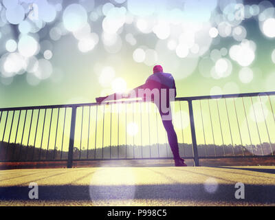Sportsman doing stretching in the park. Silhouette against sun, sports concept.  Hipster filter. Stock Photo