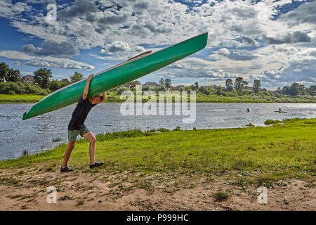 Polotsk, Belarus - July 6, 2018: One teen boy carrying their canoes on their shoulders after kayak slalom. Stock Photo