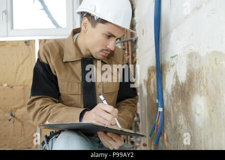 young technician inspecting electric cables at construction site Stock Photo