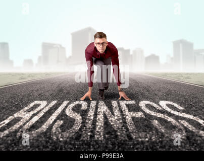 Young determined businessman kneeling before business text  Stock Photo