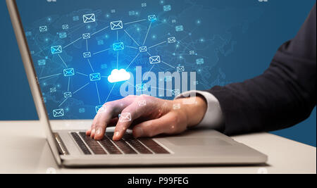 Businessman hand sending a bunch of messages on laptop with cloud Businessman hand sending a bunch of messages on laptop with cloud
