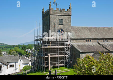 Men man people erecting building scaffolding on village church exterior in summer Hawkshead Cumbria England UK United Kingdom GB Great Britain Stock Photo
