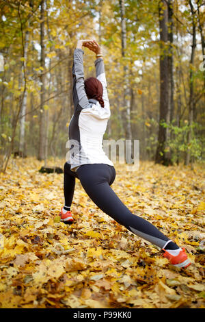 Autumn photo from back of sporty woman stretching in forest Stock Photo