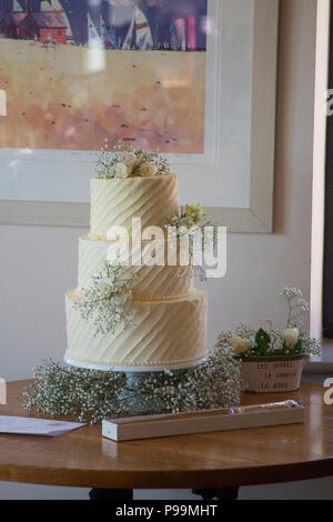 Three tiered wedding cake covered in buttercream icing and real flowers Stock Photo