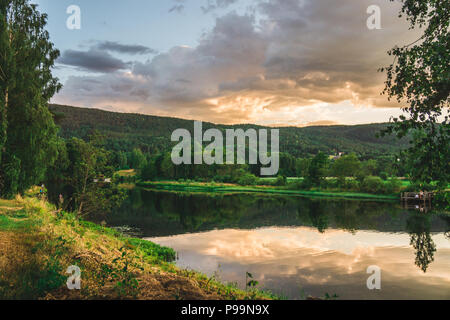 The sun setting over the mountains, lighting up the sky in a shower of light. In Telemark, Norway. Stock Photo