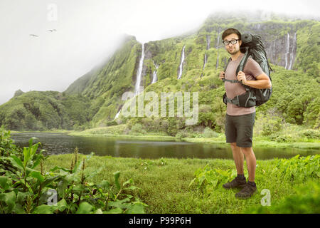 Hiker with backpack in front of a tropical waterfall Stock Photo