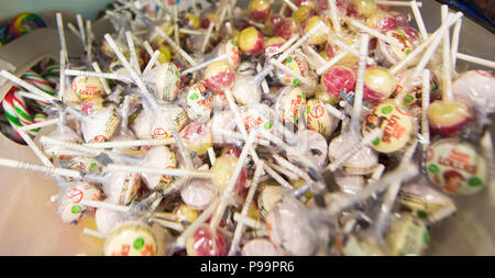 Great big pile of colourful traditional sugar lollipops with paper sticks in cellophane wrapping tipped up in a sweet shop Stock Photo