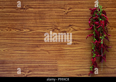 Big bunch of chilli peppers or chili drying on a wooden wall. Organic spices hanging at home with wooden background. Copy space to add text. Stock Photo