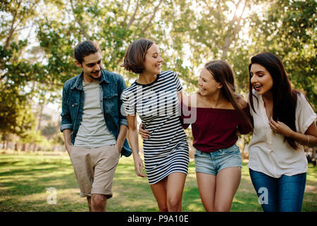 Portrait of three women and young man walking and enjoying together at park. Group of friends walking together in the park. Stock Photo