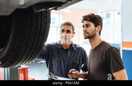 Mechanic and assistant working at auto repair Stock Photo - Alamy