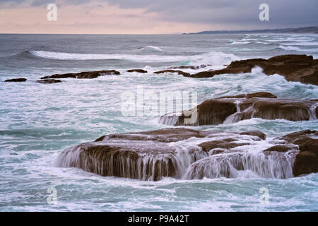 Evening approaches and sea birds take flight over Oregon’s central coastline at Yachats. Stock Photo