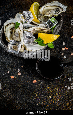 Fresh raw seafood, oysters with lemon and ice on a light blue background Stock Photo