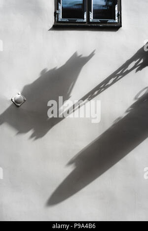 Diagonal shadow from the lantern on an uneven painted wall with a window Stock Photo