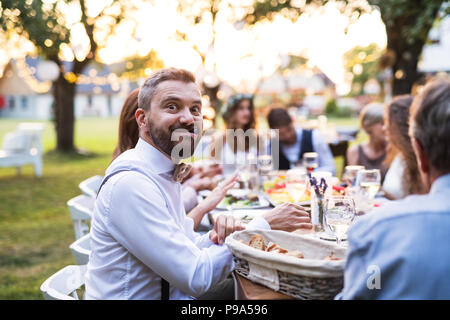 Guests eating at the wedding reception outside in the backyard. Stock Photo